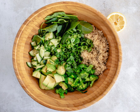 Overhead view of a bowl of quinoa salad with spinach, broccoli, spinach, avocado and spring onion