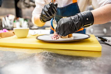 chef cooking food. Chef's hands in gloves cooking fried thin pancakes crepe stuffed potato with herring fish on kitchen