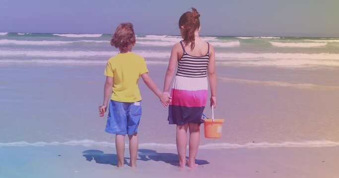 Rear view of caucasian brother and sister standing at the beach