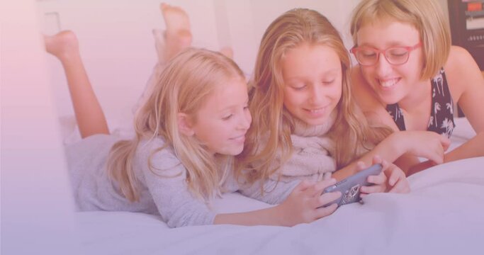 Three caucasian sisters using smartphone together while lying on the bed