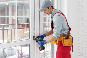 Man fixing lock to window with electric screwdriver