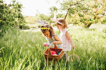 Easter egg hunt. Group Of Children Wearing Bunny Ears Running To Pick Up colorful Egg On Easter Egg Hunt In Garden. Easter tradition - 496278032