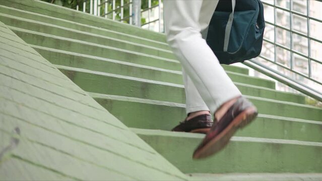 Close up legs of businessman walking stepping up the stairs in rush hour to work in hurry at urban.