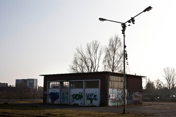 Laternenfpfahl an dem Turnschuhehängen vor einem alten Zweckbau mit Graffitis