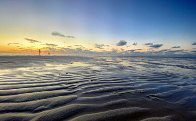 View of the setting sun shining on the Sea and reflected on the beach, clouds with sun-shining edges. Landscape. High quality photo