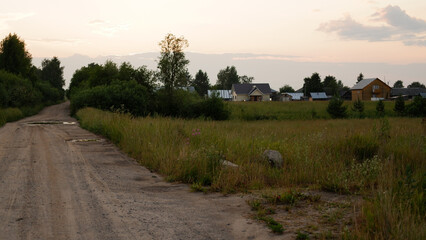 Beautiful rustic summer landscape with road. Old wooden log houses. Vologda region