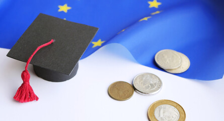 Graduation cap with coins on European flag. Study abroad concept. Student scholarship banner