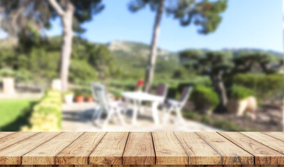 Empty wooden table with blurred luxury garden with swimming pool on background