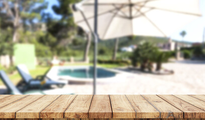 Empty wooden table with blurred luxury garden with swimming pool on background