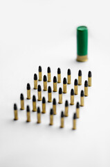 high angle view of bullets near blurred shotgun shell on white background.