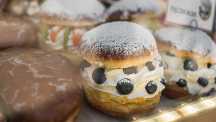 Traditional Polish donuts with berries and whipped cream in a glass on a bakery showcase in Krakow,...