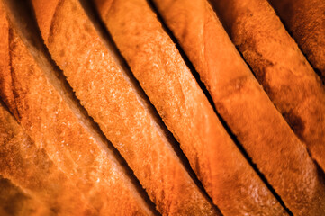 slices of white bread close up as a background. backdrop of rough textured surface chopped pieces loaf of natural organic food. top view