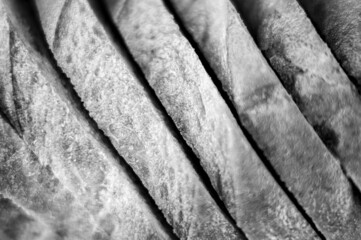slices of white bread close up as a background. gray backdrop of rough textured surface chopped pieces loaf of natural organic food. top view. toned in black white color