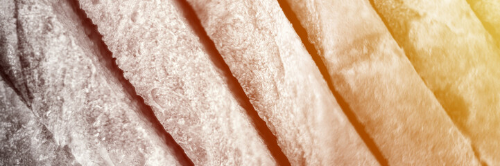 slices of white bread close up as a background. gray backdrop of rough textured surface chopped pieces loaf of natural organic food. top view. toned in black white color. banner. flare