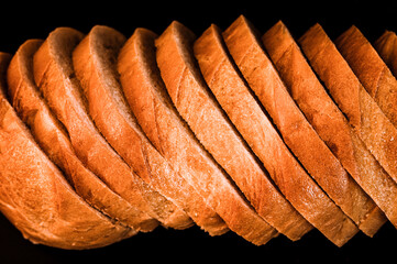 slices of white bread close up isolated on a black background. rough textured surface chopped...