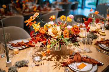 modern table serving for wedding in autumn style. orange flowers, autumn leaves, brown and orange napkins