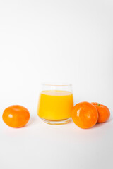 Glass of fresh orange juice with three citrus mandarin fruits near. Isolated on the white background.