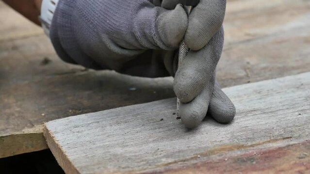 Worker using a nail punch/Travailleur se servant d'un chasse clou
