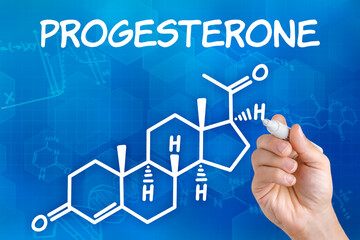Hand with pen drawing the chemical formula of progesterone