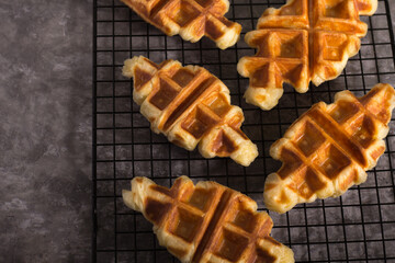Group of Croffle waffles arranged on a metal cooling rack with a dark, textured backdrop.