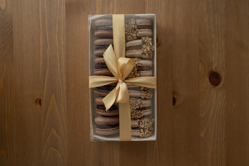 Sweet dessert macaroons in a box decorated with a ribbon, on a wooden table.
