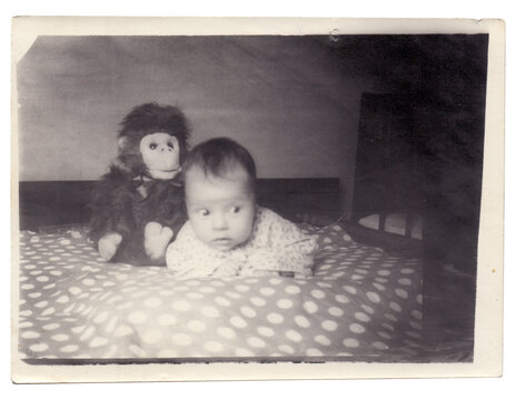 Vintage photo of little baby girl with monkey toy