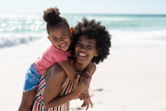 Portrait of cheerful african american mother and daughter enjoying at beach on sunny day