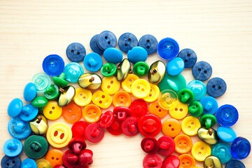 Rainbow from multicolored button on wooden background