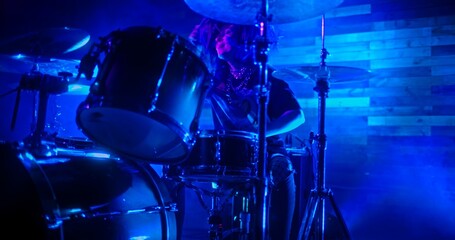 Professional Drummer emphatically playing the drums in twinkling blue lights - obrazy, fototapety, plakaty