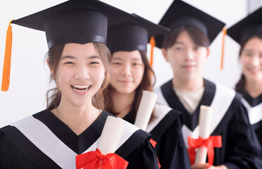 Smiling asian girl student  graduate and classmates standing with diplomas in hands