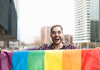 Happy gay man having fun holding rainbow flag symbol of LGBTQ community