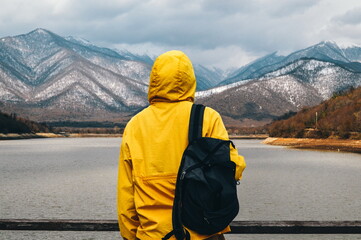 Man against the backdrop of mountains in a bright yellow jacket