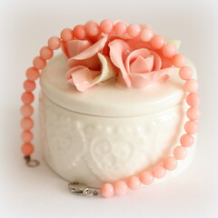 Pink coral bracelet and porcelain jewelry box isolated on white background, on table.