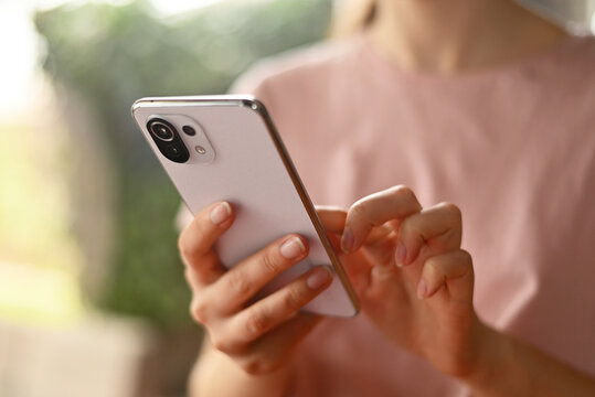 Poland, Poznan - 29 march, 2022. close-up woman uses modern smartphone Xiaomi 11 Lite flipping through news feed at home. to write a message. selective focus