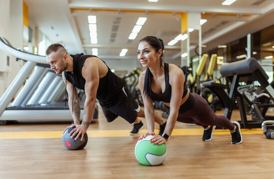 Athletic man and woman are training together with medicine ball in modern gym. Healthy lifestyle - Powered by Adobe