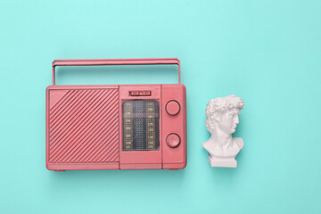 David bust with retro radio receiver on turquoise background. Flat lay
