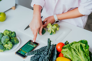 Go vegan. Close up woman cutting broccoli while cooking healthy dish according to the active online...