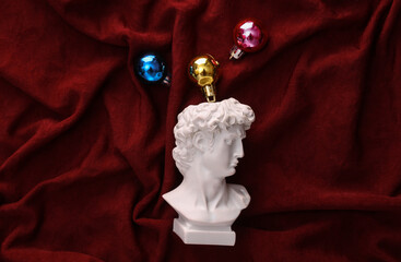 David plaster bust with Christmas balls on red crumpled silk background