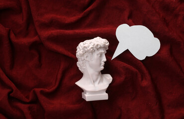 David plaster bust with dialog cloud on red crumpled silk background