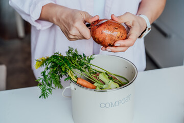 Compost the kitchen waste, recycling at home. Woman cleaning sweet potato and putting vegetables...