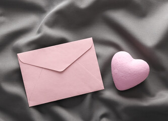 Pink envelope with heart on folded gray silk background