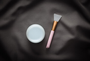 Cream jar on gray fabric crumpled background