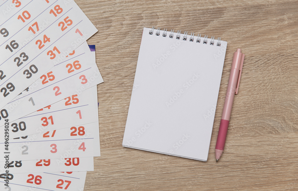 Poster paper calendar with notebook on wooden table. top view