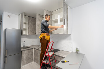 electrician, a male electrician is standing on the stairs holding wiring in his hands and stripping, repairing light at home, repair work, call master, electrician man repairing light