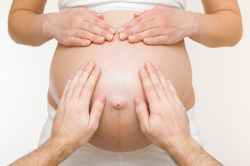 Young adult man hands touching pregnant woman big naked belly. Emotional loving pregnancy time. Baby expectation. Closeup. Point of view shot. Isolated on light gray background. Front view.