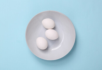 Bowl with eggs on a blue background