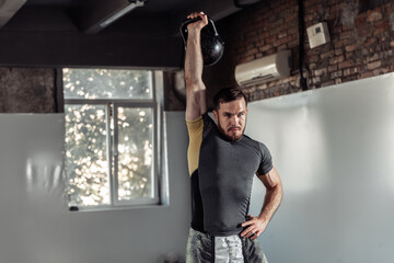 Young athletic man exercising with a kettlebell in a gym