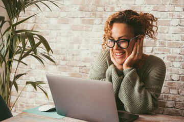 Cheerful attractive woman doing video call conference with computer connection. Home technology...