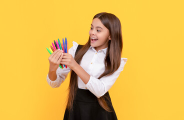 Happy girl child hold felt-tips yellow background, school stationery