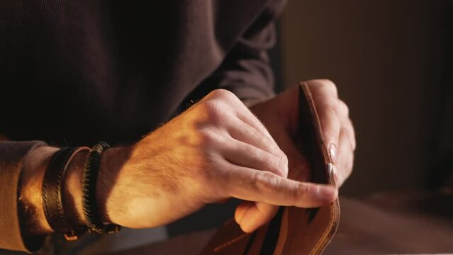 tanner makes genuine leather wallet, professional craftsman, closeup, indoor, authentic, business. Handiwork. lubricates edges with cream